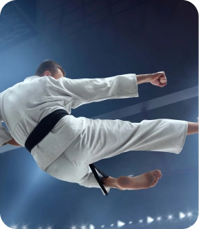 Athlète de karaté exécutant un coup de pied haut puissant lors d'une compétition d'arts martiaux en salle.